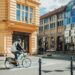 A cyclist rides in a city with stunning architecture.