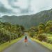 woman walking in black concrete road in front of mountain