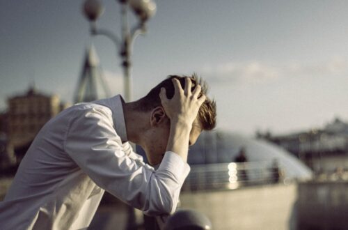 man in white dress shirt covering face with his hands